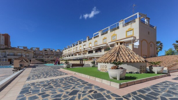 A hotel with a tiled courtyard, a pool, and a building with balconies. - 032 - Parque y Playa 001 - comfortHOLIDAYS (Santa Pola)
