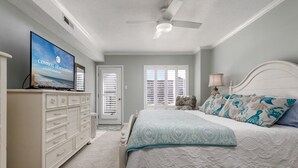 A bedroom with a bed, a dresser, a television, and a ceiling fan. - Fully remodeled 2 bedroom condo on the ocean block in North OC (Ocean City)