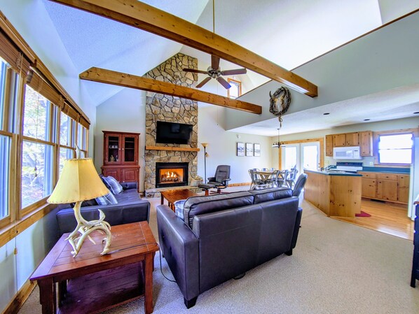 A spacious living room with a stone fireplace, leather sofas, and a dining area with a large table.