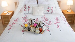 A neatly made bed with a floral bedspread, a tray of breakfast items, and a canopy bed. - Apartament Na Wierchu (Poronin)
