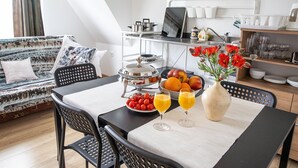 A dining area with a table set for breakfast, including fruits, a vase of flowers, and glasses of orange juice. - Apartament Na Wierchu (Poronin)