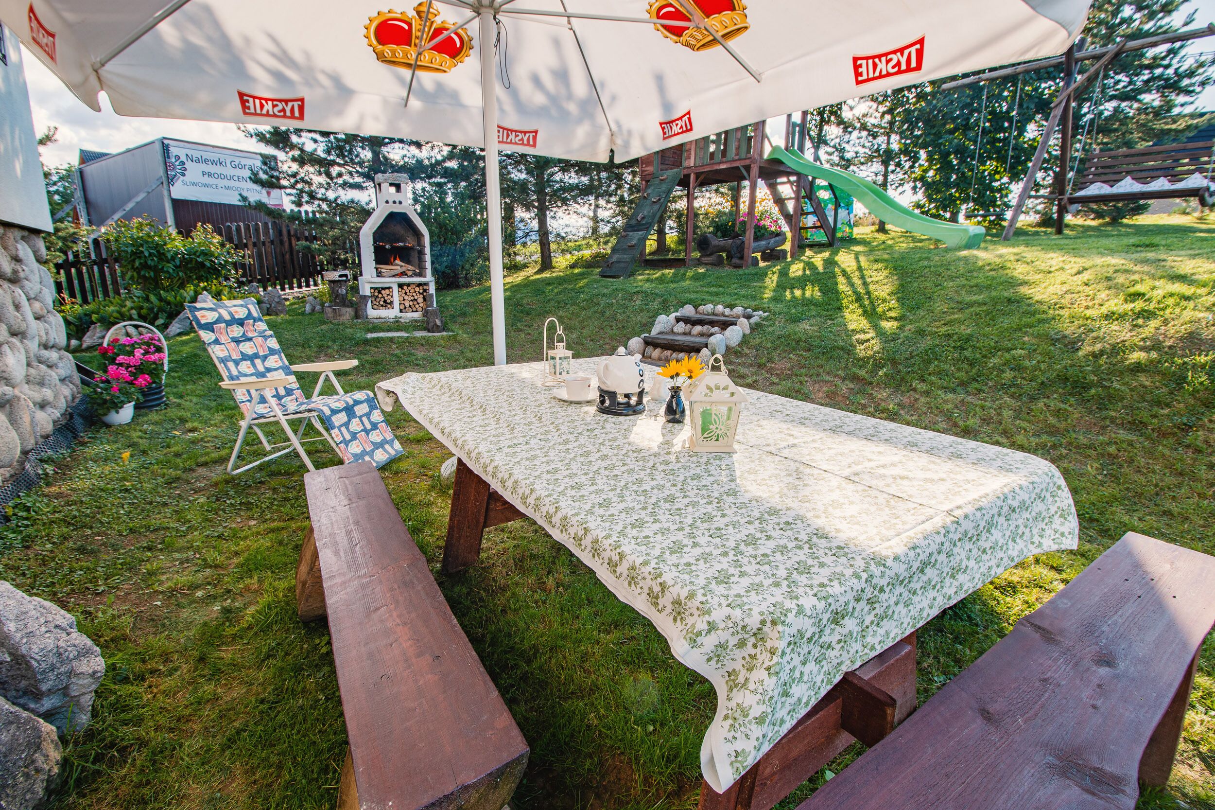 Un área de comedor al aire libre con una mesa bajo un toldo, rodeada de bancos de picnic.