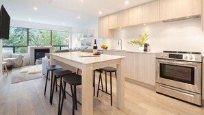 A modern kitchen with a central island, stainless steel appliances, and large windows. - Luxury 3BR/2BA Creekside: Hot tub, A/C, Secure Bike Storage, Mountain Views (Whistler)