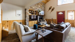 Una sala de estar acogedora con chimenea de piedra, vigas de madera y una puerta roja.
