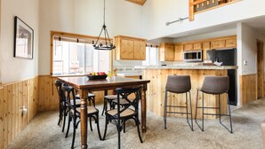 A spacious kitchen with wooden cabinets, a large island with bar stools, and a hanging light fixture. - Two-Cabin Buyout + 2 Hot Tubs | Walk to Snow Summit | Jumper & Jackhorn (Big Bear Lake)