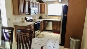 A kitchen with wooden cabinets, stainless steel appliances, and a tiled floor. - Palma Sola Pool Home Bradenton (Bradenton)