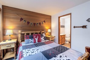 Ein gemütliches Schlafzimmer mit einem Holz-Kopfteil, einem Bett mit gestecktem Quilt, Nachttischen mit Lampen und einem Spiegel an der Wand.