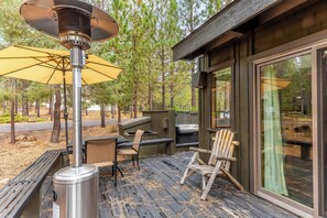 Eine Terrasse mit Terrassenheizer, Sitzgelegenheit und Blick auf den umliegenden Wald.