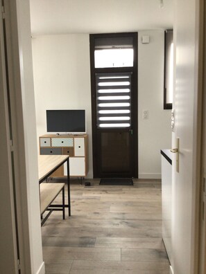 A modern kitchen with a built-in oven, a dining table, and a TV on a cabinet.