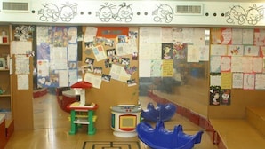 A classroom with educational posters, a bulletin board, a red and green toy table, and a blue toy boat on the floor. - Rimonim Mineral Tiberias (Tiberias)