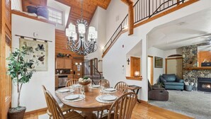 A dining room with a wooden table set for six, a chandelier, and a staircase leading to an upper level. - Walk-in Log Cabin with Fireplace & Screened-in Balcony - Heart of Branson (Branson)