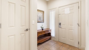 A hallway with two white doors, a wooden console table with a vase of flowers, and a framed picture on the wall. - 1 Bedroom Walk-in Golf Condo feat. Sunroom with a Beautiful Property View (Branson)