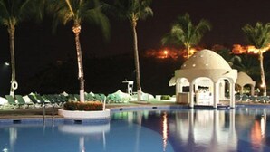 A nighttime pool area with palm trees and a gazebo. - Tesoro Manzanillo (Manzanillo)