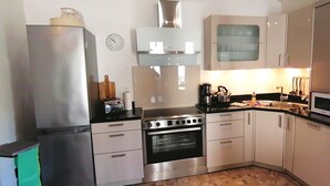 Una cocina compacta con refrigerador, estufa, horno, microondas y un reloj en la pared.