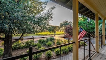 A covered outdoor area with a view of a road, a flag, and a tree.