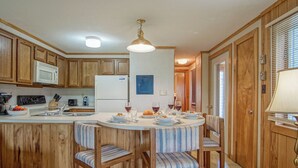 Una cocina con armarios de madera, un refrigerador blanco, un microondas y una mesa de comedor con sillas.