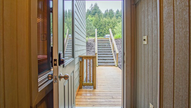 Una terraza de madera que conduce a una escalera frente a un edificio con vistas a árboles.