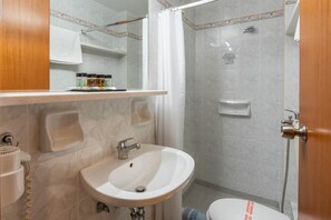 A bathroom with a sink, mirror, shower, and toilet. - Poseidonio (Piraeus)