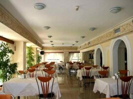 Un amplio comedor interior con varias mesas y sillas, un techo alto con iluminación empotrada y vistas al exterior a través de grandes ventanales.