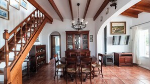 Un espace repas agrémenté d’un escalier en bois, d’un lustre et d’un meuble avec des portes en verre.