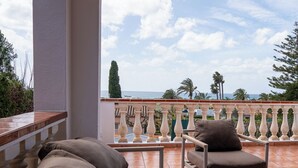 Un balcon avec vue sur la mer, un canapé et un fauteuil.