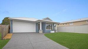 Une maison de plain-pied avec un garage, une véranda et une pelouse bien entretenue.