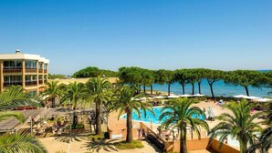 Un complexe hôtelier doté d’une piscine, de palmiers et offrant une vue sur la mer.