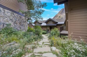 A stone pathway leading to a house with a stone facade and a wooden deck. - Gad Valley Lodge - ski-in/out to Snowbird (Alta)
