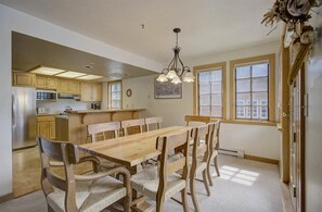 Eine Küche mit Holzausbau, einem Edelstahlkühlschrank, einer Mikrowelle und einem Esstisch mit sechs Stühlen.