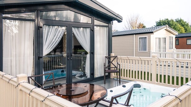 A covered outdoor area with a hot tub, a table, and chairs. - Luxury Lodge in Stunning Surroundings (York)