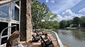 A deck with outdoor seating, a stone building, and a view of a lake. - Camelot on Lake Hamilton | Dock, Hot Tub + Theater (Hot Springs)