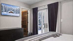 A bedroom with a bed, a dresser, a television on the wall, and a door leading to a balcony. - Après Ski Retreat at Voss Ski Haus 949 (Park City)