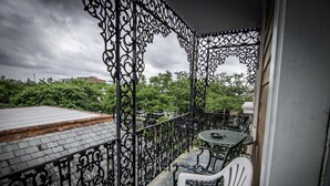 Un balcon avec une balustrade en fer forgé, une petite table et une chaise blanche.