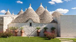 A traditional stone house with conical roofs, surrounded by a well-maintained lawn and potted plants.