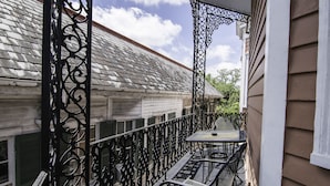 Un balcon avec une balustrade en métal, une table et deux chaises.