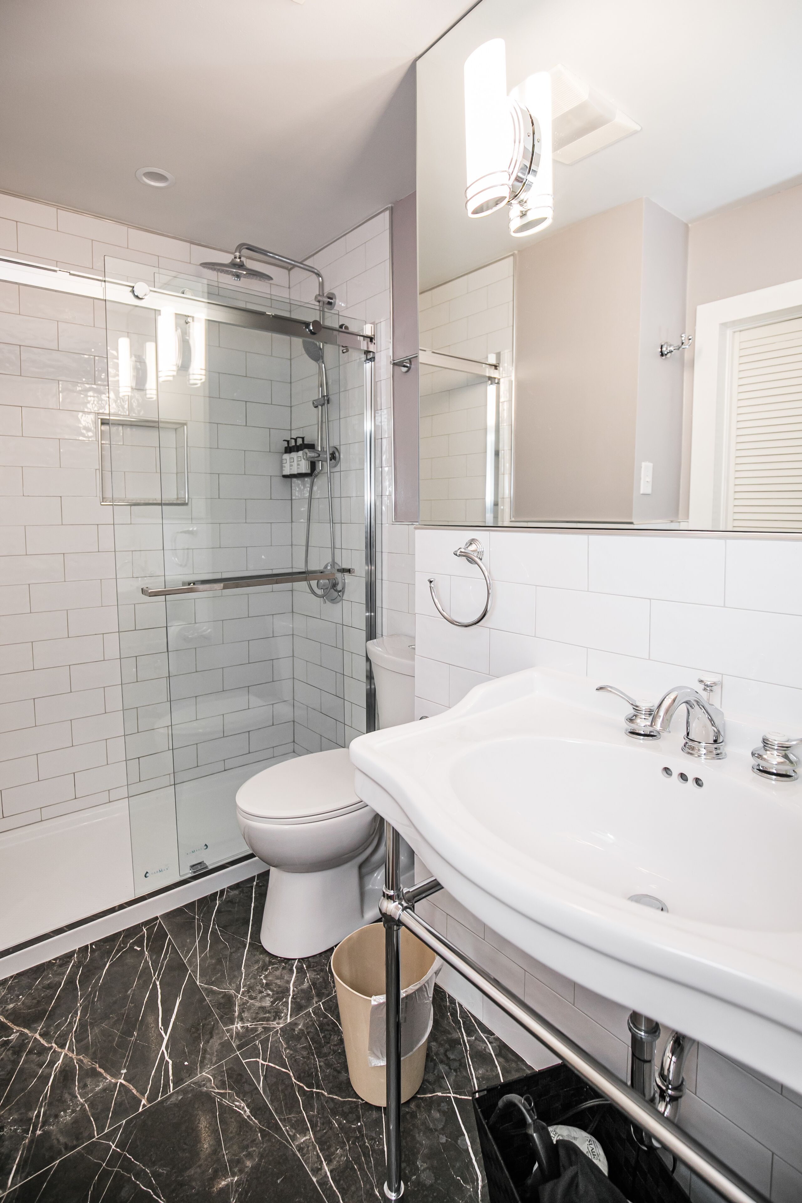 Een moderne badkamer met een douchecabine van glas, een wit toilet en een ruime wastafel met spiegel erboven.
