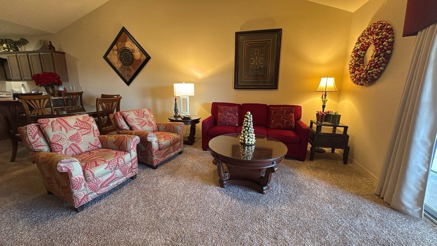 A living room with a red sofa, patterned armchairs, a coffee table, and a fireplace.