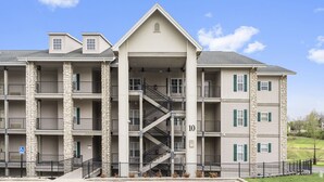 A multi-story apartment building with a central staircase, balconies, and a gated entrance. - 2 King BR, 2BA Golf Condo - Private Balcony with View (Branson)