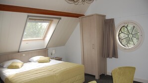 Une chambre à coucher comprenant un lit, une armoire, une chaise, une fenêtre et un puits de lumière.