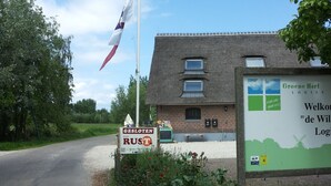 Un bâtiment situé en zone rurale, avec une enseigne, un drapeau et une route.