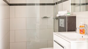 Une salle de bain moderne avec une douche à parois de verre, des toilettes blanches et un lavabo agrémenté d’articles de toilette.