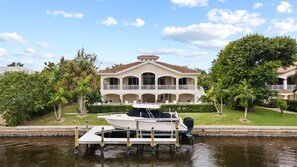 Une propriété située au bord de l’eau, comprenant une grande maison, un quai et un bateau.