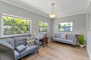 Ein Zimmer mit zwei Sofas, einem Schreibtisch und einem Sessel.