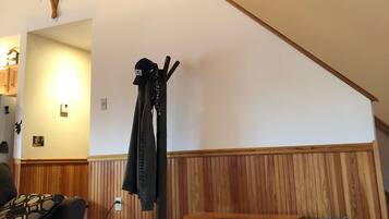 Une pièce chaleureuse avec un plafond en pente, des lambris en bois, un porte-manteau, un banc et un panier en osier.