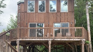 A wooden cabin with a deck and stairs leading to a balcony. - Cozy Cabin on the River (D'Iberville)