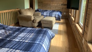 A cabin with wooden walls and ceiling, two beds with blue and white checkered bedding, a sofa, and a mounted TV. - Cozy Cabin on the River (D'Iberville)