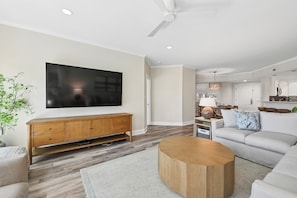 A modern living room with a flat-screen TV, wooden entertainment unit, and a round coffee table.