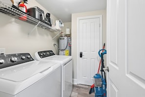 A laundry room with a front-loading washer and dryer, a water heater, and a door with a security lock.