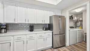Una cocina moderna con armarios blancos, electrodomésticos de acero inoxidable y un salpicadero de azulejos.