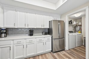 A modern kitchen with white cabinetry, stainless steel appliances, and a tiled backsplash.